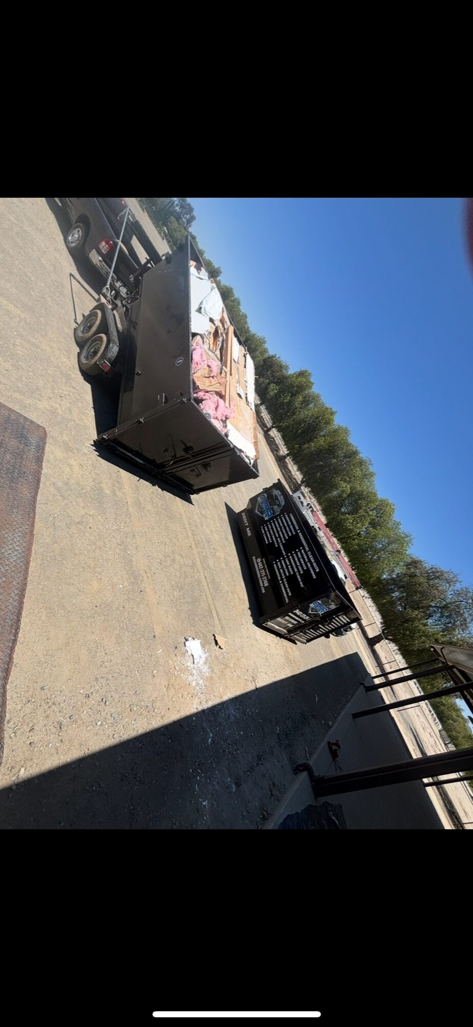 Rental dumpster in a residential driveway loaded with renovation debris and drywall next to an OSR-branded dumpster